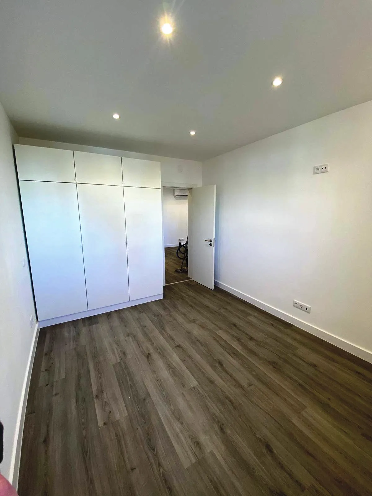 Roupeiro encastrado em lacado branco num quarto, produzido e montado pela SUDSTUDIO