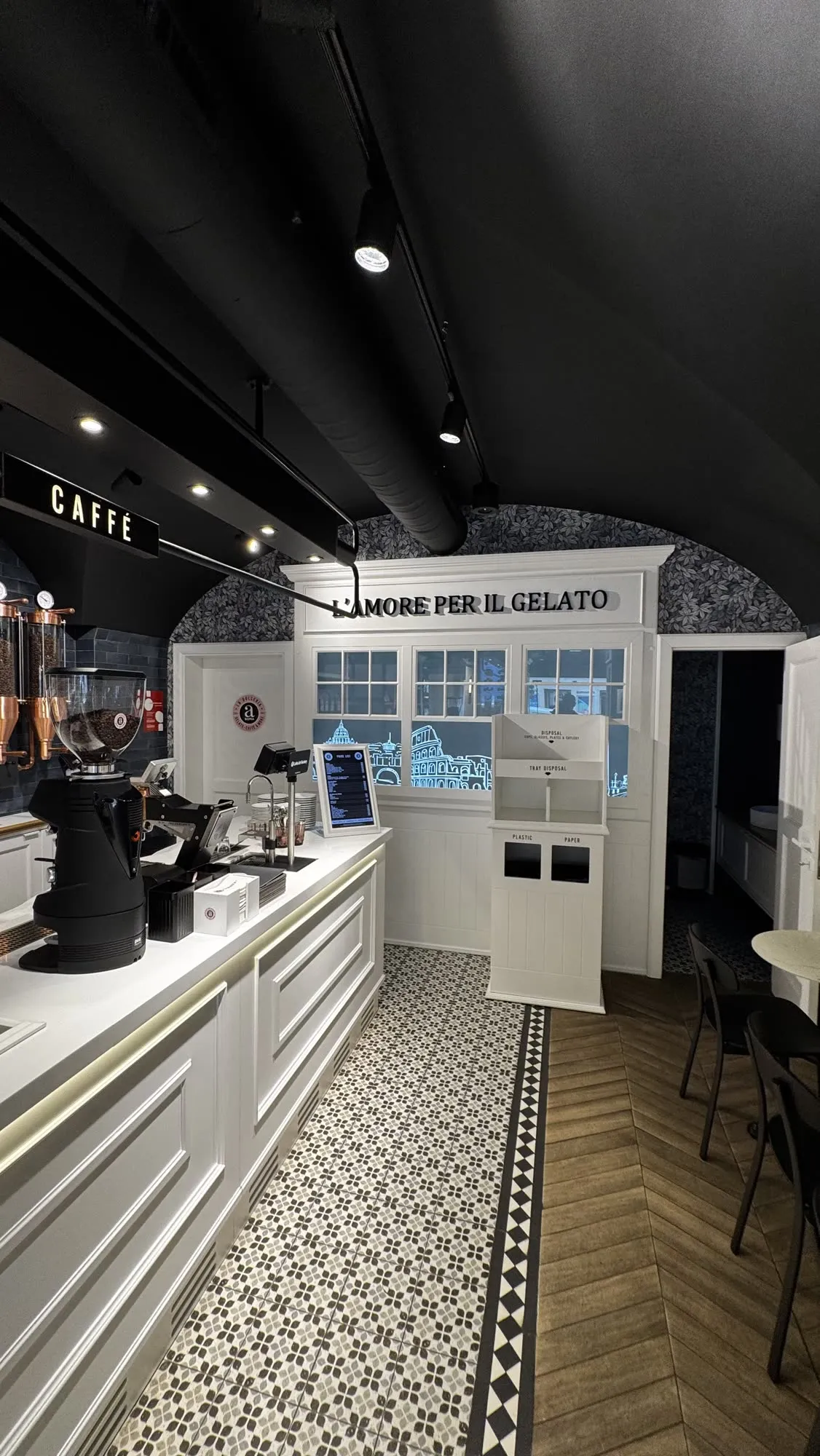 Zona de cafetaria com a máquina de café e a bancada de serviço encostada ao arco