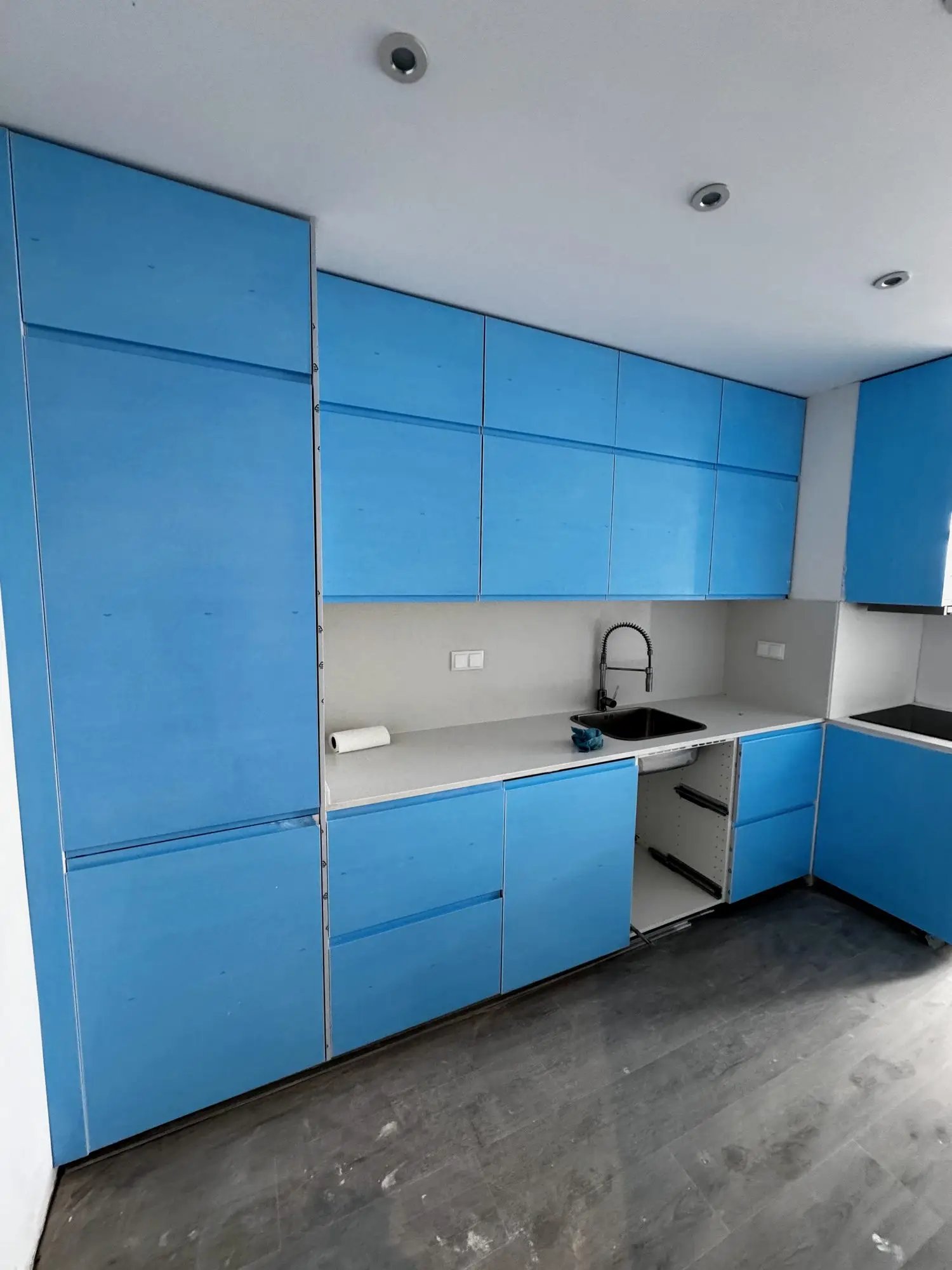 A cozinha em fase de instalação, ainda com a película azul de proteção sobre os armários lacados