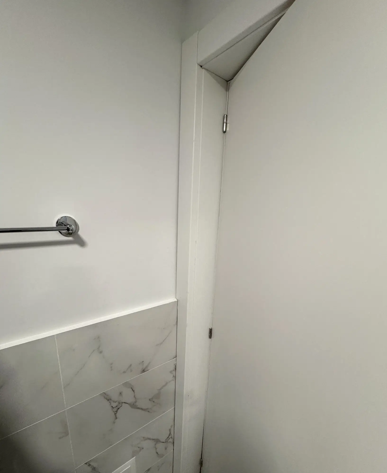 Casa de banho depois da obra, com revestimento marmoreado e porta de acabamento branco