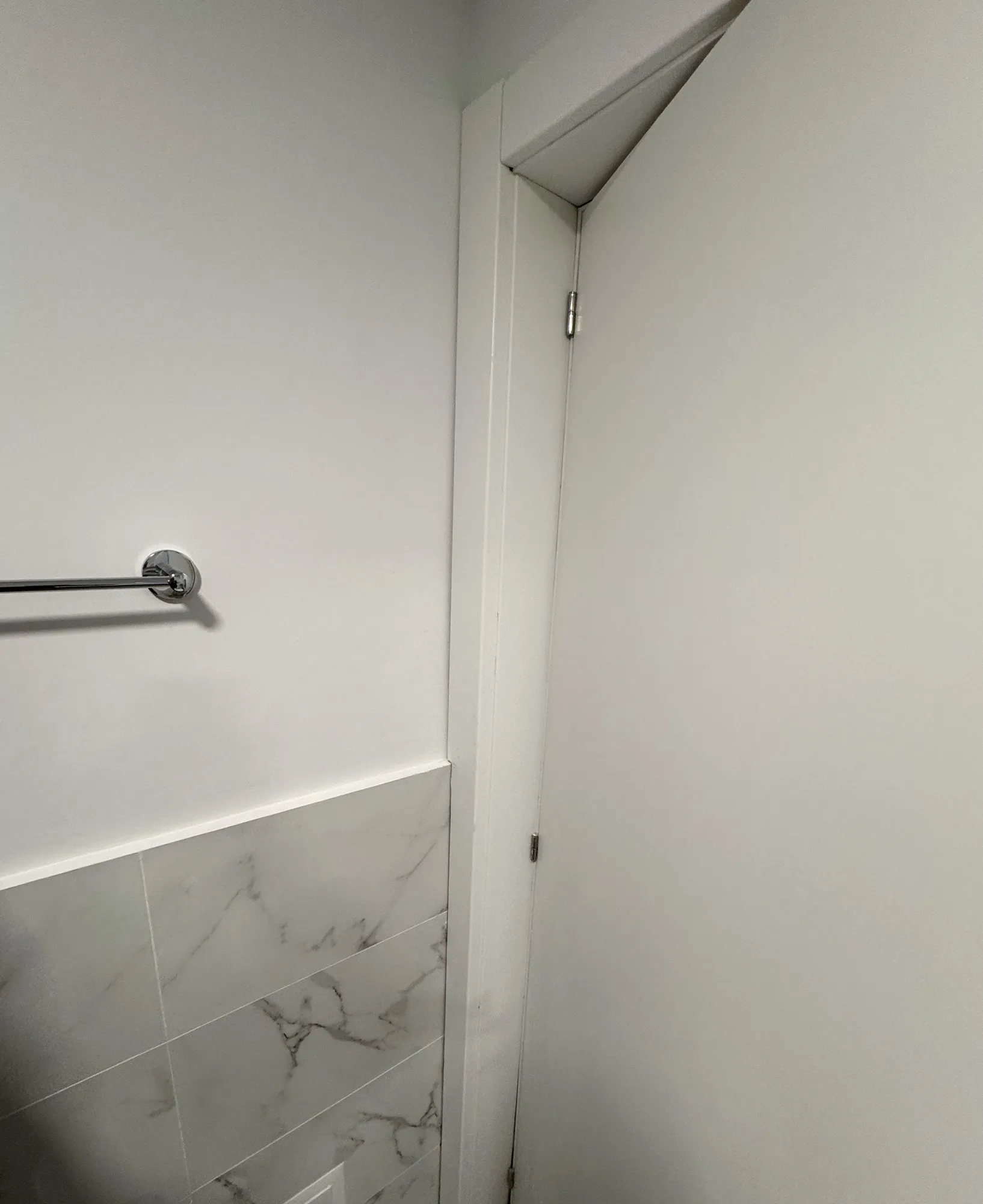 Casa de banho depois da obra, com revestimento marmoreado e porta de acabamento branco