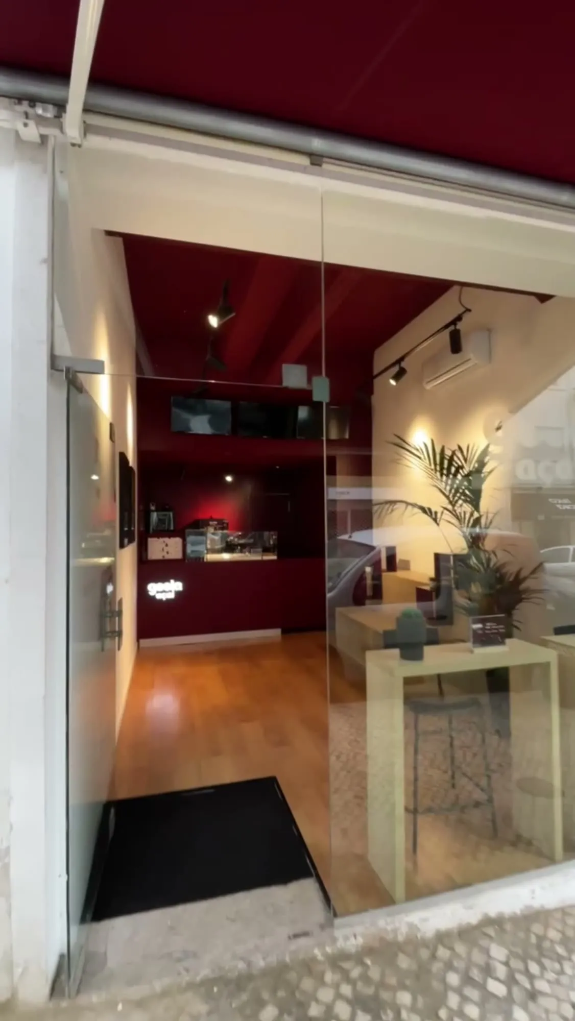 A loja acabada vista da rua, com a montra em vidro e o interior vermelho iluminado