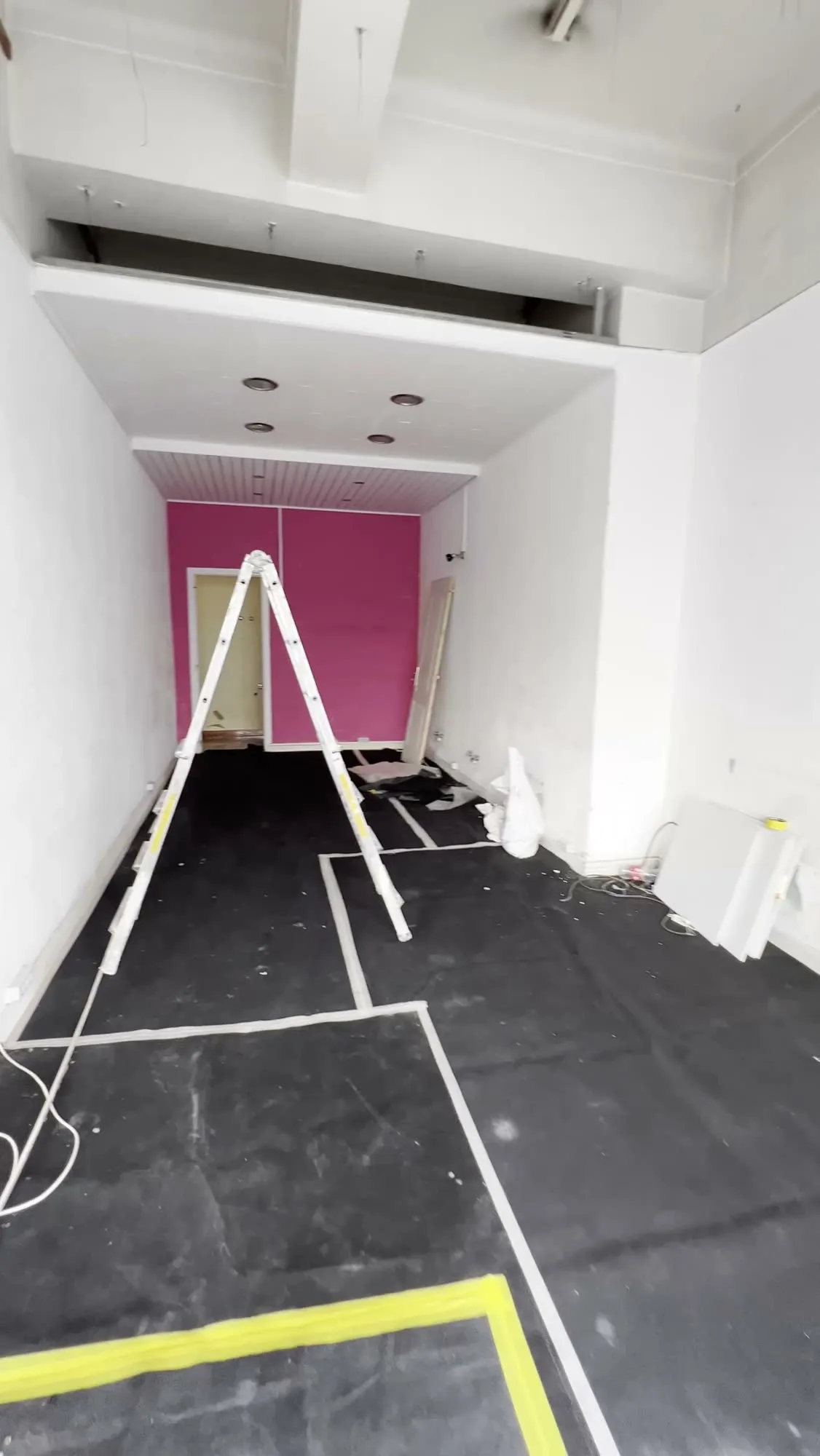 Interior durante a obra, com o pavimento protegido e a implantação da loja marcada no chão