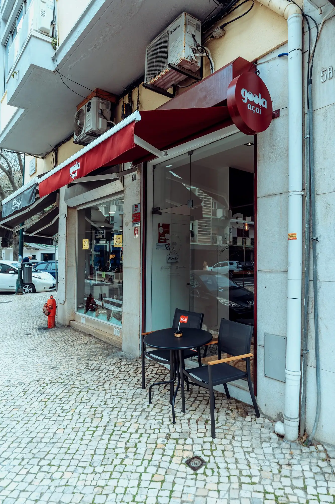 Fachada da loja em Campo de Ourique, com o toldo vermelho e uma mesa na calçada