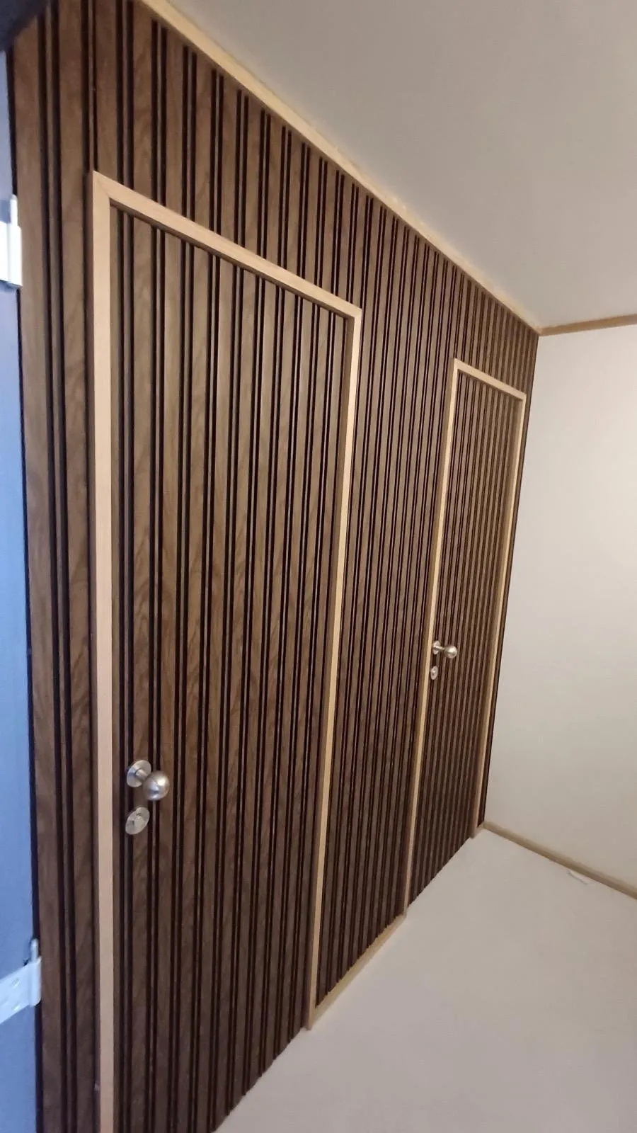 Pormenor das portas embutidas no ripado de madeira, com puxadores discretos